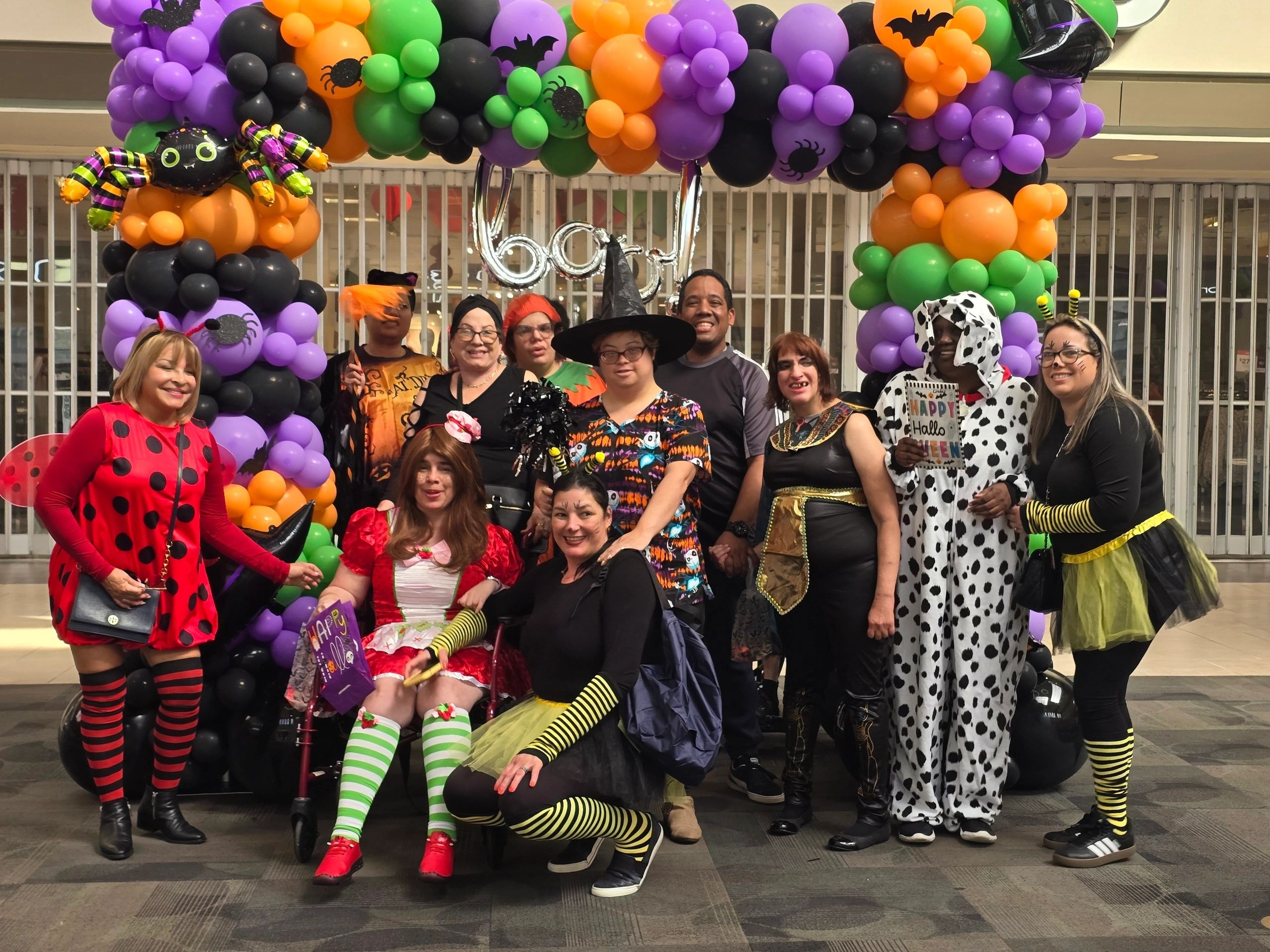 MPD consumers in Halloween costumes under a balloon arch